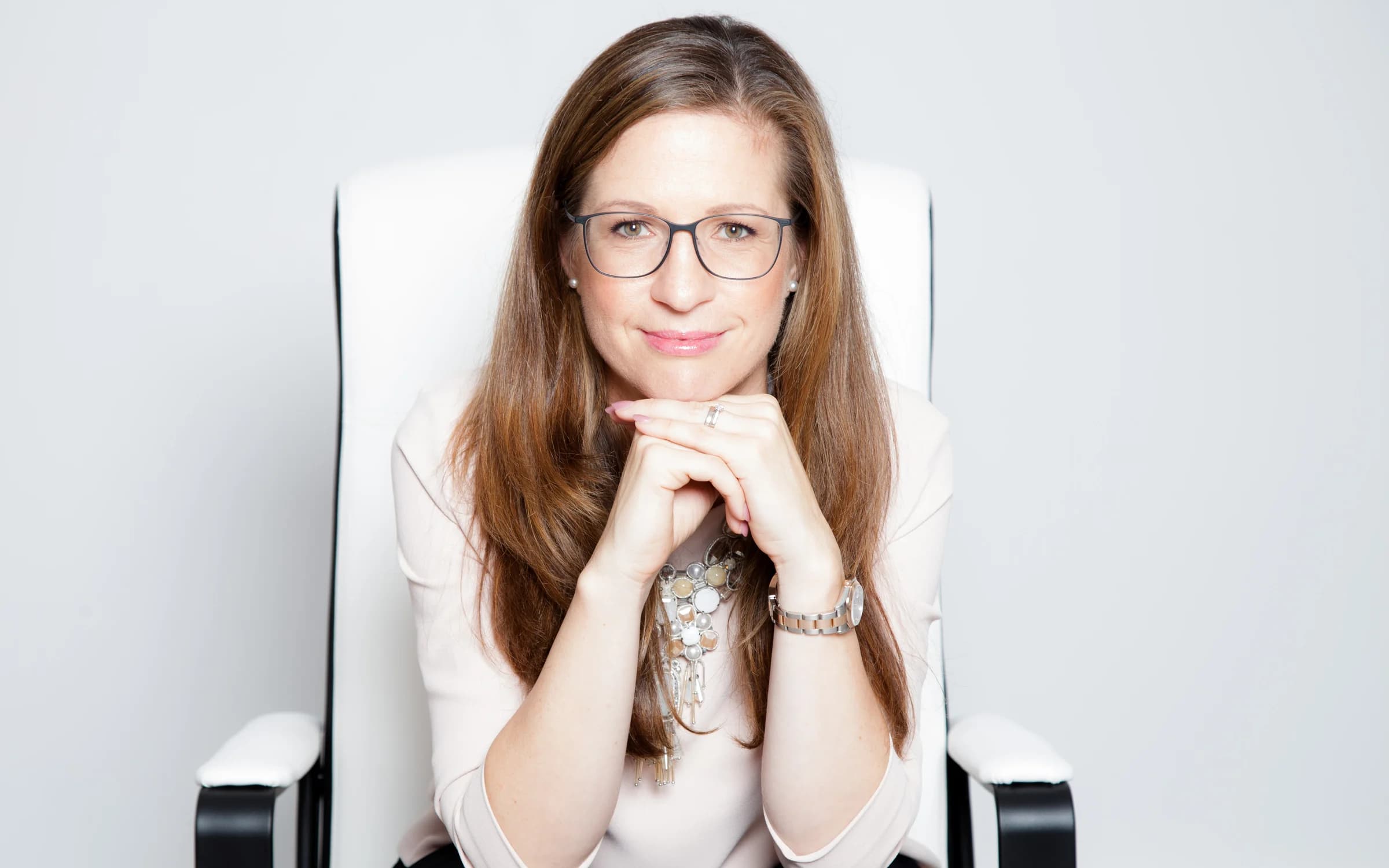 Eva-Maria Kraus sitzt frontal zur Kamera, das Kinn auf die gefalteten Hände gestützt